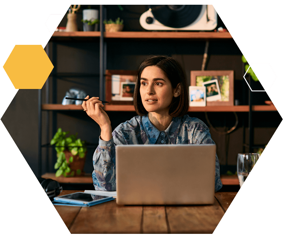 Woman sat at desk on laptop looking away thinking